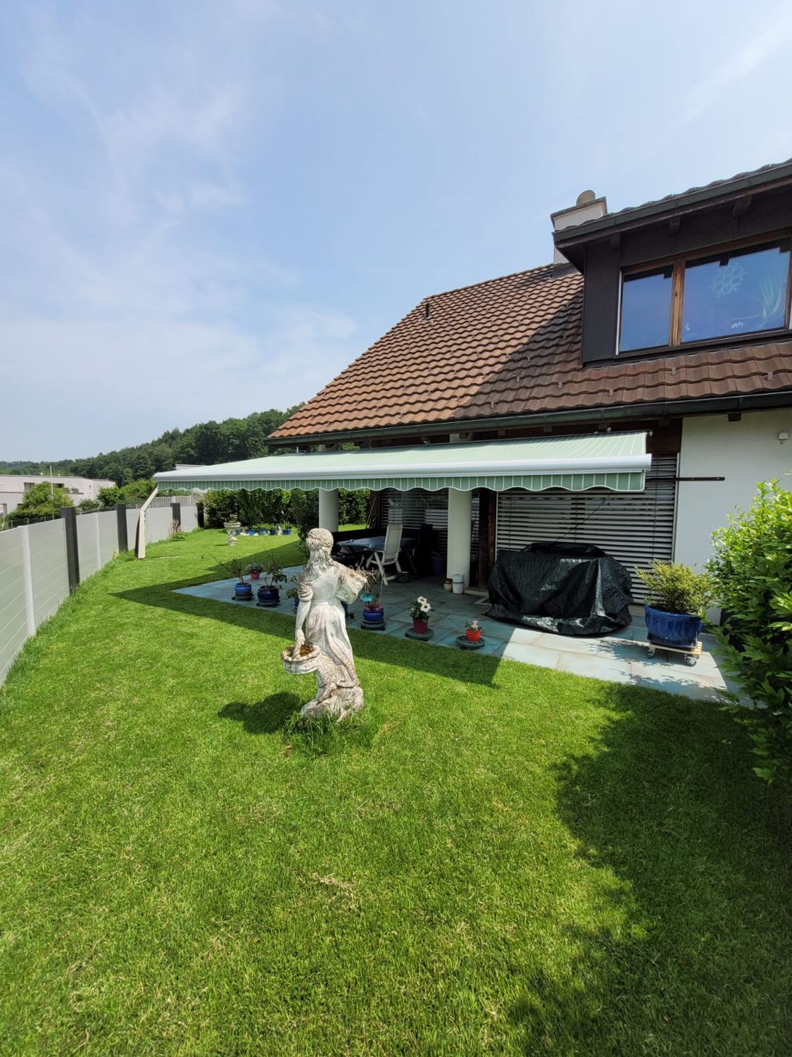 Markise an einem Einfamilienhaus mit Garten