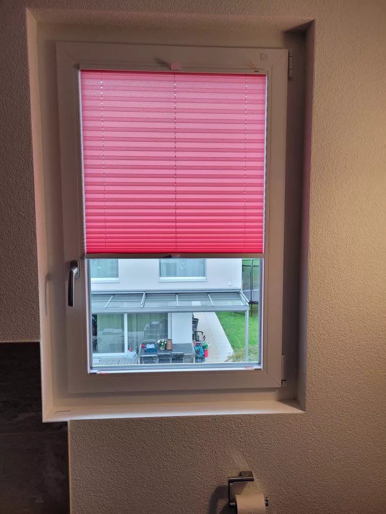 Rotes Plissee an einem Kippfenster